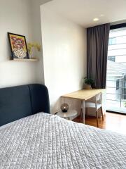 Cozy bedroom with bed, side table, and study desk near large window