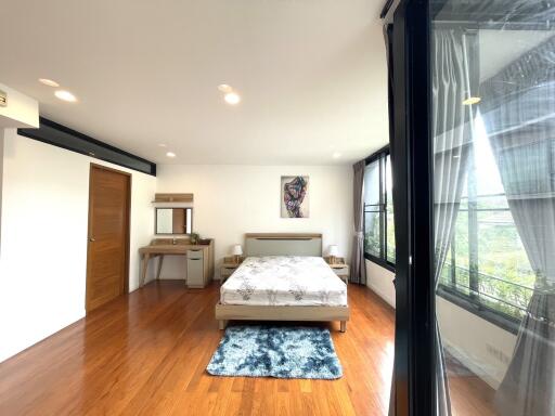 Spacious bedroom with hardwood floor and large windows