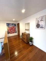 Well-lit hallway with artwork and wooden dresser