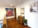 Well-lit hallway with artwork and wooden dresser