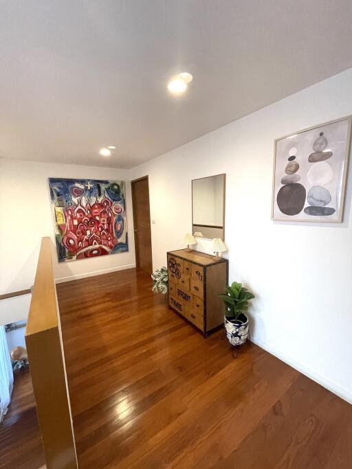 Well-lit hallway with artwork and wooden dresser