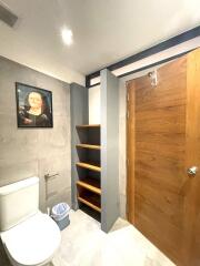 Bathroom with wooden door and wall shelves