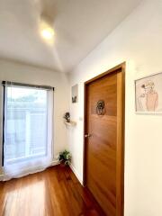 Wooden door in a bright hallway with a large window and simple decor