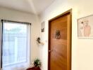 Wooden door in a bright hallway with a large window and simple decor