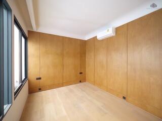 Spacious bedroom with wooden panel walls and large window