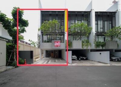 Modern townhouse exterior with trees and a for sale sign