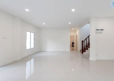 Spacious modern living room with white walls, large windows, and tiled floor