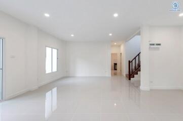 Spacious modern living room with white walls, large windows, and tiled floor