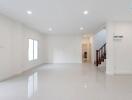 Spacious modern living room with white walls, large windows, and tiled floor