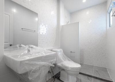 Modern white-tiled bathroom with a sink and toilet