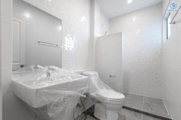 Modern white-tiled bathroom with a sink and toilet