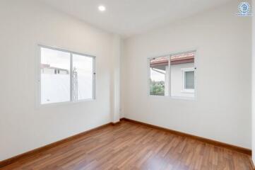 Empty bedroom with wooden floor and large windows