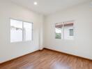 Empty bedroom with wooden floor and large windows