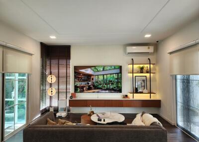 Modern living room with brown sofa, mounted TV, and large windows