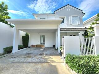 Exterior view of a white two-story house with driveway and carport