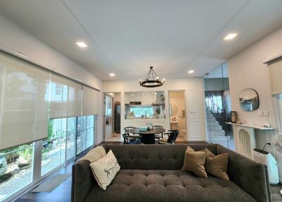 Modern living room with a sofa, dining table, and large windows