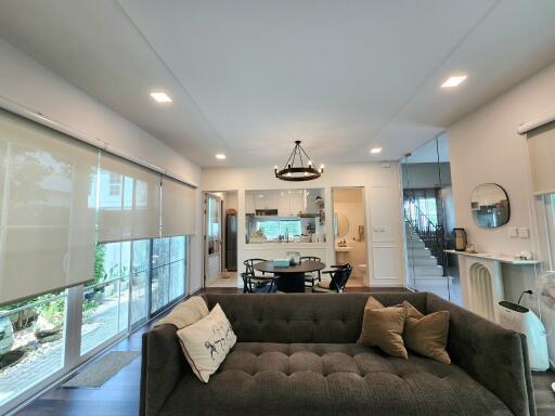 Modern living room with a sofa, dining table, and large windows