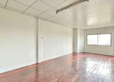 Empty room with wooden flooring and ceiling tiles