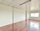 Empty room with wooden flooring and ceiling tiles