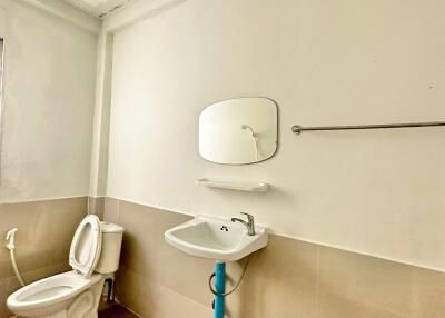 Modern bathroom with toilet, sink, mirror, and towel rack