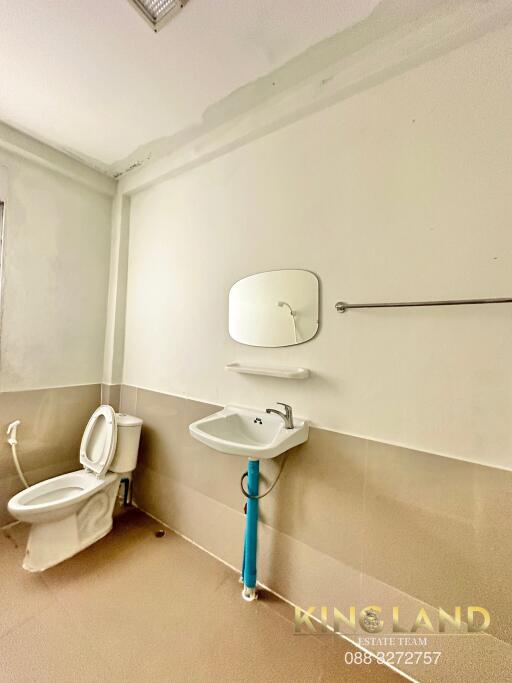 Modern bathroom with toilet, sink, mirror, and towel rack