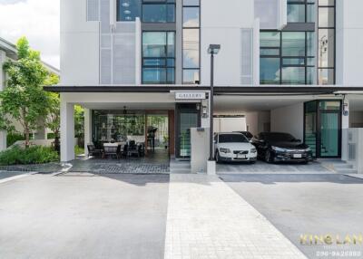 Front view of a modern residential building with a covered parking area and outdoor seating