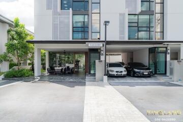 Front view of a modern residential building with a covered parking area and outdoor seating