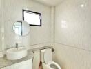 Modern bathroom with white tiles, a countertop basin, toilet, and window