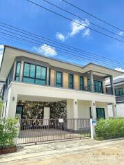 Modern two-story house with a stone facade, large windows, and gated driveway