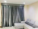 Living room with a grey sectional sofa and large grey curtains