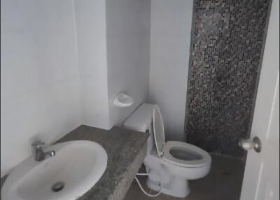 Compact bathroom with sink, toilet, and tiled wall