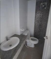 Compact bathroom with sink, toilet, and tiled wall