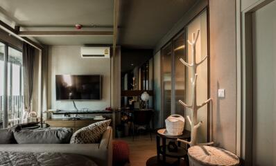 Modern living room with a TV mounted on the wall, a couch, and balcony access