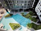 Aerial view of a modern apartment building with a swimming pool and landscaped areas