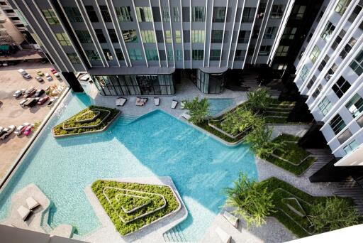 Aerial view of a modern apartment building with a swimming pool and landscaped areas