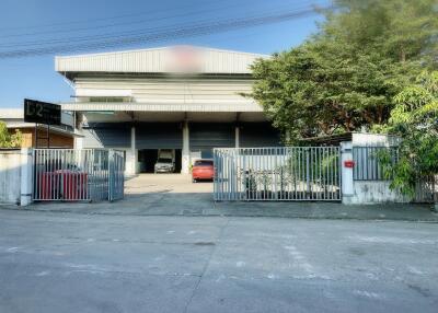 Industrial building with gated entrance, parking area, and surrounding greenery