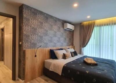 Modern bedroom with decorative wallpaper, double bed, and large window with curtains