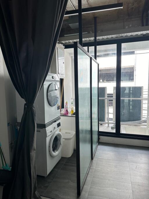 Laundry area with stacked washer and dryer, next to a large window