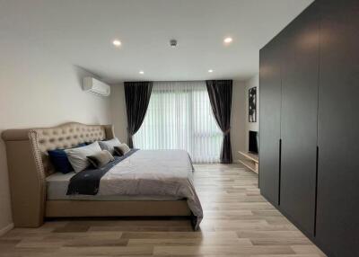 Modern spacious bedroom with double bed, air conditioner, large window, and wardrobe