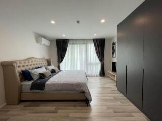 Modern spacious bedroom with double bed, air conditioner, large window, and wardrobe