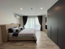 Modern spacious bedroom with double bed, air conditioner, large window, and wardrobe