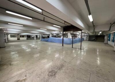 Spacious building with exposed ceiling beams and fluorescent lighting