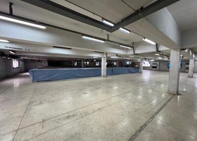 Spacious empty industrial or commercial area with overhead lighting and tiled floors