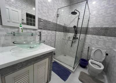 Modern bathroom with glass shower, vanity, and toilet