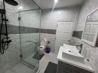 Modern bathroom with glass shower, toilet, and sink