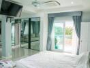 Modern bedroom with large mirrors, TV, and balcony view