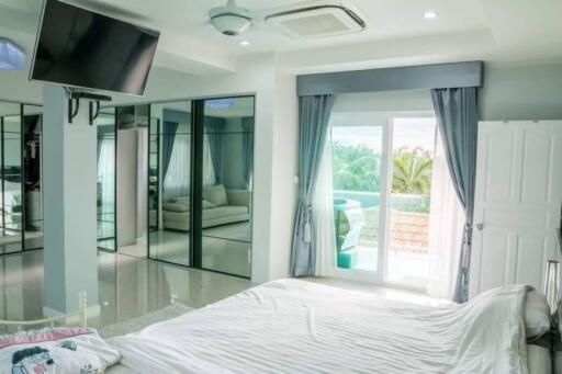 Modern bedroom with large mirrors, TV, and balcony view