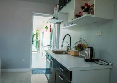 Modern kitchen with white countertops and cabinets, featuring appliances and decorations.