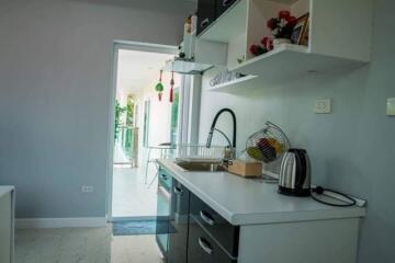 Modern kitchen with white countertops and cabinets, featuring appliances and decorations.