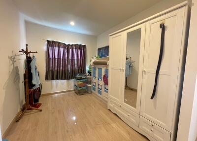 Well-lit bedroom with wooden floor, wardrobe, and children